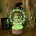 Round engraved acrylic LED table sign glowing green on a wooden base beside candles