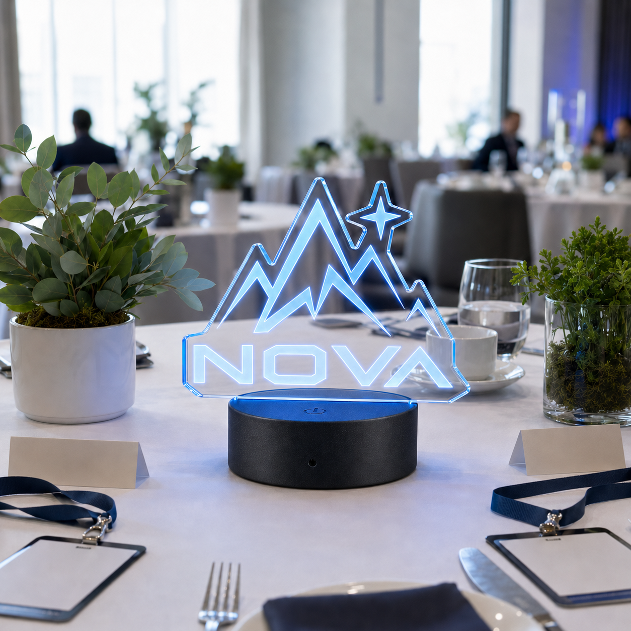 Clear die-cut LED acrylic logo centerpiece with round black base at a corporate conference