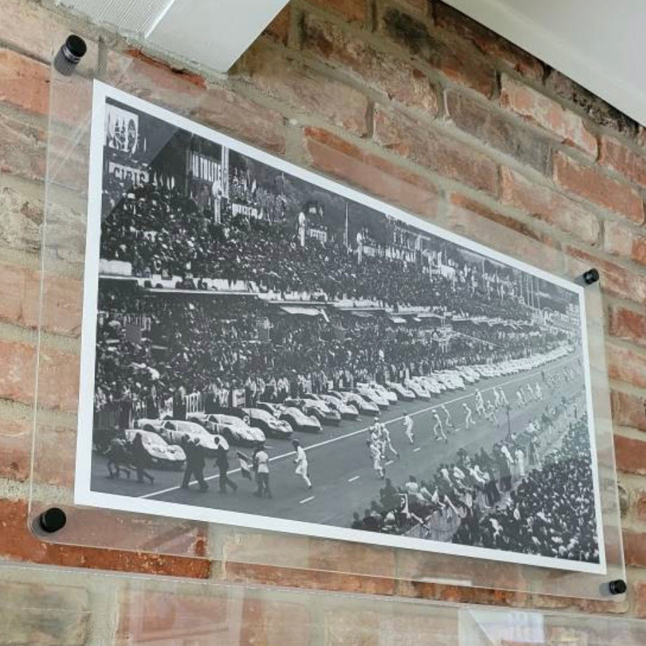 Clear floating acrylic picture frame with round corners holding a black and white panoramic photo on an exposed brick wall