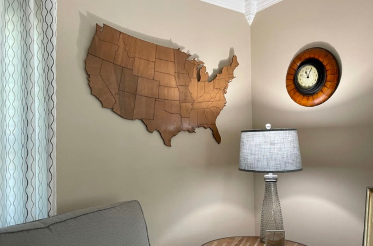 Stained wooden USA map cutout wall art hanging in a living room corner above a lamp