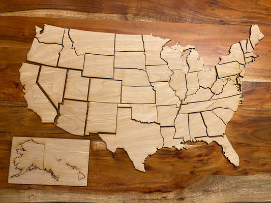 Unfinished wooden USA map cutout laid flat on a walnut table with all state pieces plus Alaska and Hawaii